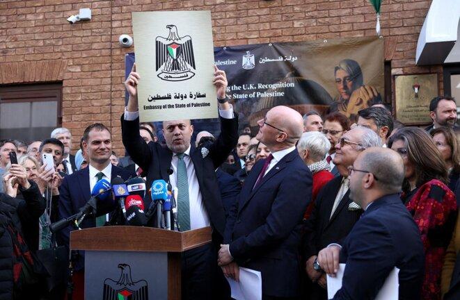 Le chef de la Mission palestinienne au Royaume-Uni, Husam Zomlot, brandit une plaque portant l'inscription « Ambassade de l'État de Palestine », lors d'une cérémonie de lever de drapeau devant leur mission à Londres, le 22 septembre 2025. © Photo Adrian Dennis / AFP